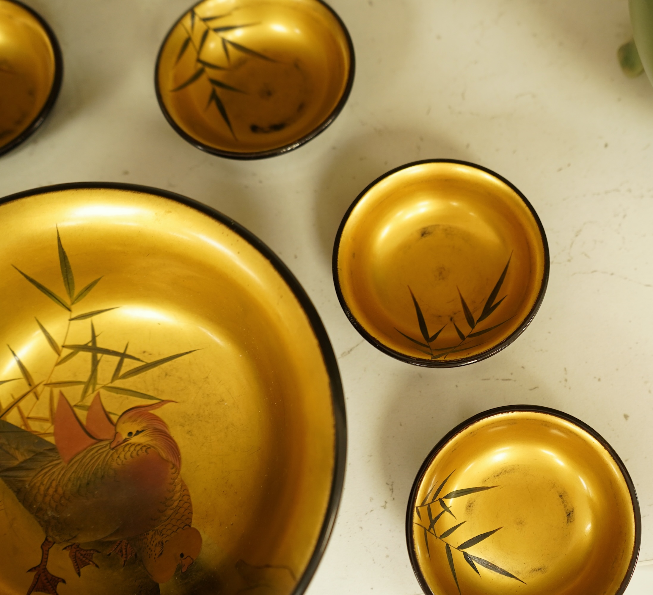 A Japanese lacquer bowl with gilt interior decorated with birds and six small dishes, largest 15cm in diameter